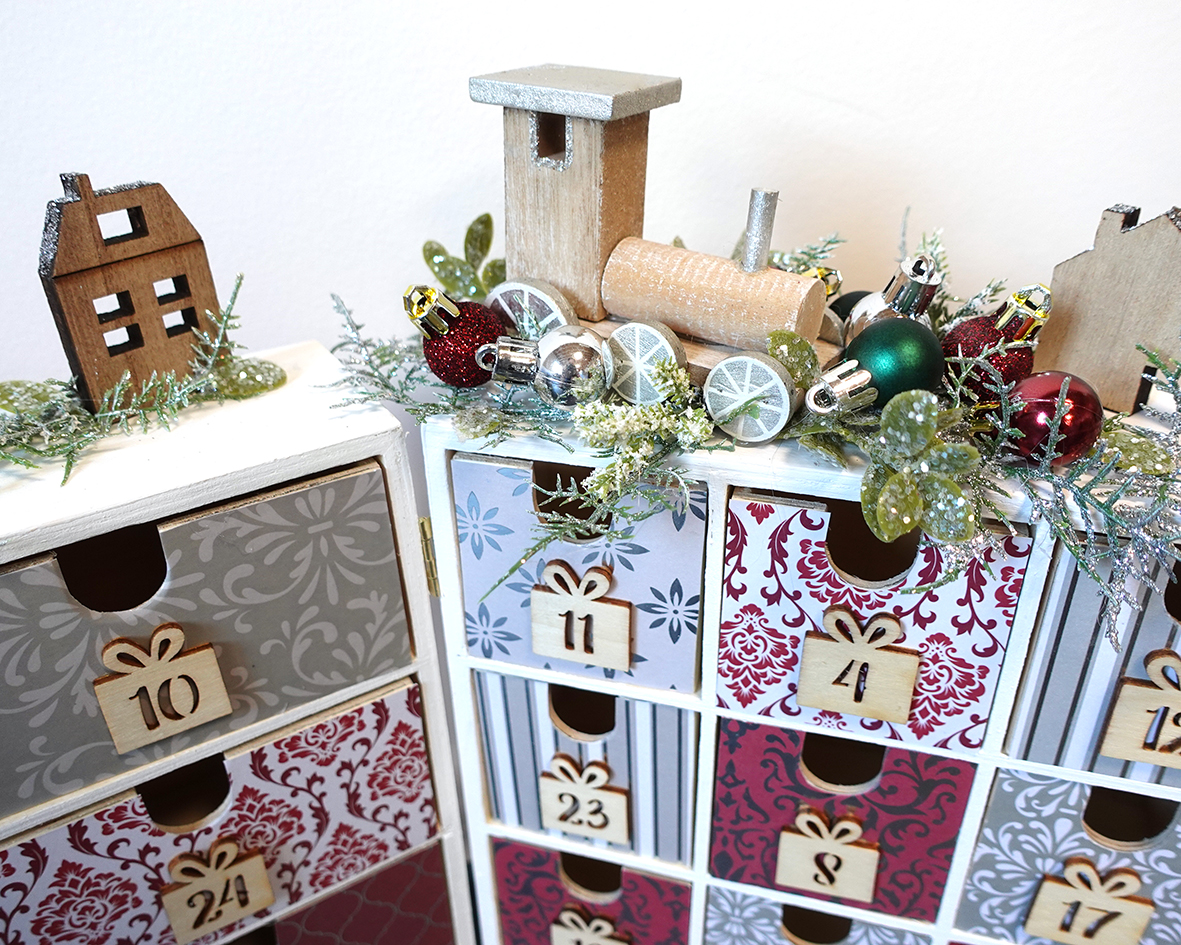 Detail na adventný kalendár v luxusnej bordovo-striebornej kombinácii s drevenými ozdobami, umelou čečinou a vianočnými guličkami.